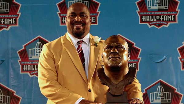 Walter Jones posing in front of his hall of fame bust