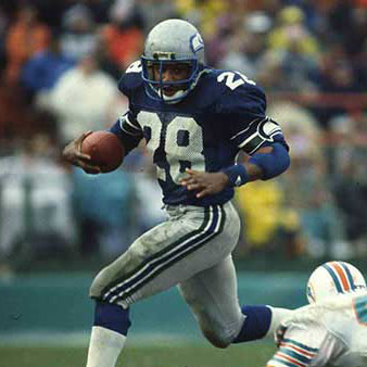 Curt Warner running from defenders on the field