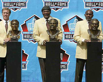 Carl Eller posing in front of his hall of fame bust along with other inductees