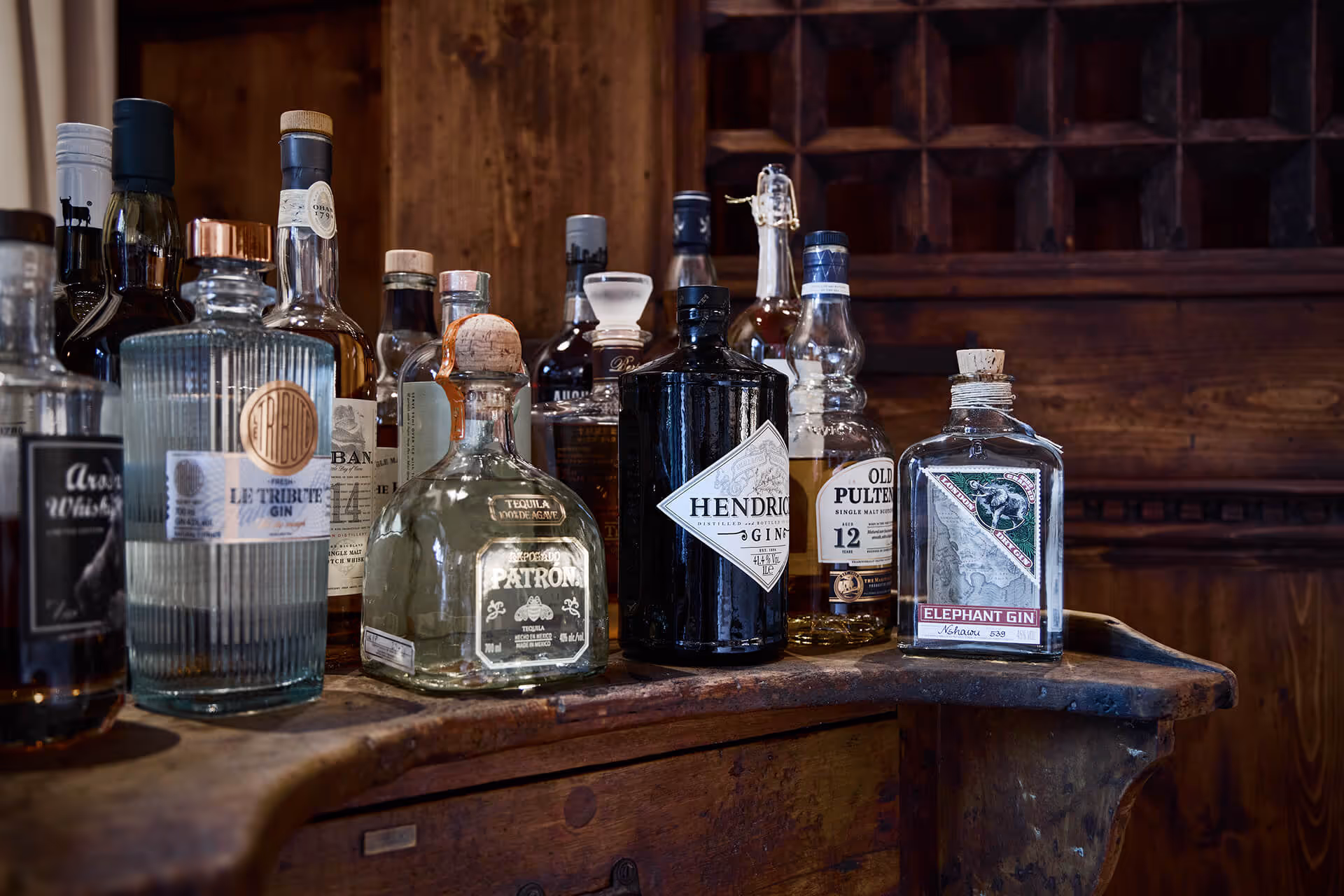 Verschiedene Flaschen mit Spirituosen wie Gin, Tequila und Whisky auf einem antiken Holztresen