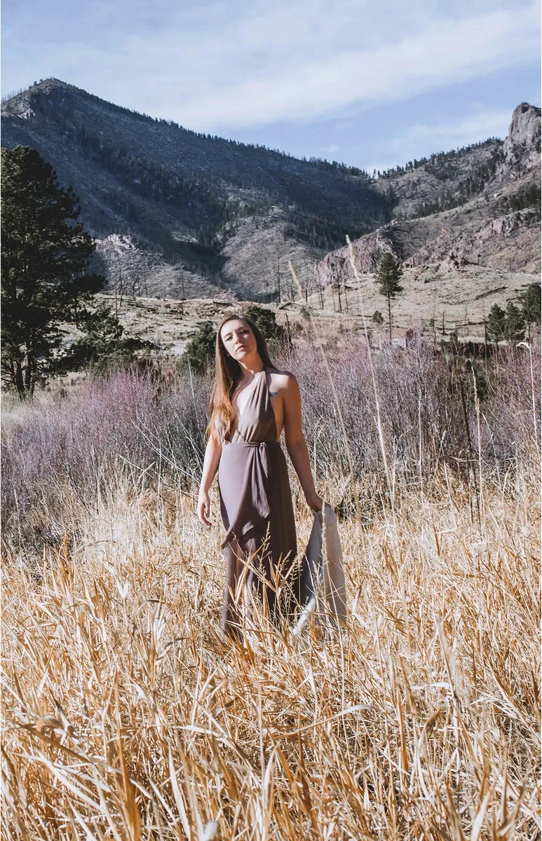 Woman posing in dried grass with scenic mountain backdrop during Shutterpix Photography outdoor portrait session