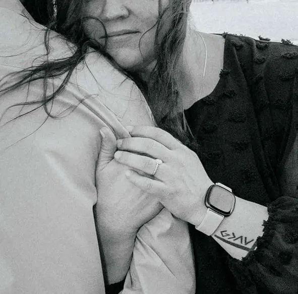 Close-up black and white image of woman resting on partner’s shoulder, showcasing engagement ring, watch, and tattoo during Shutterpix Photography session