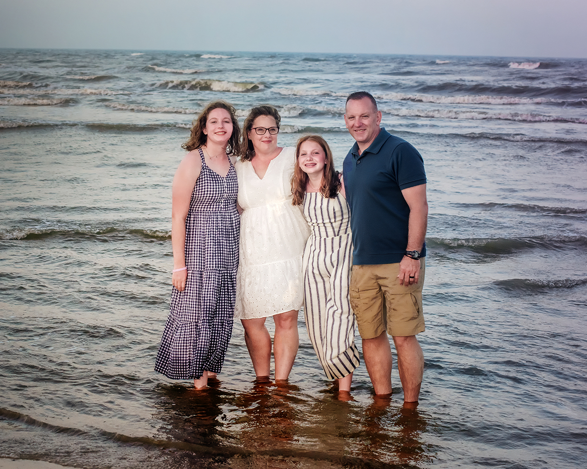 A family for a portrait session with blues and cream colors on the beach