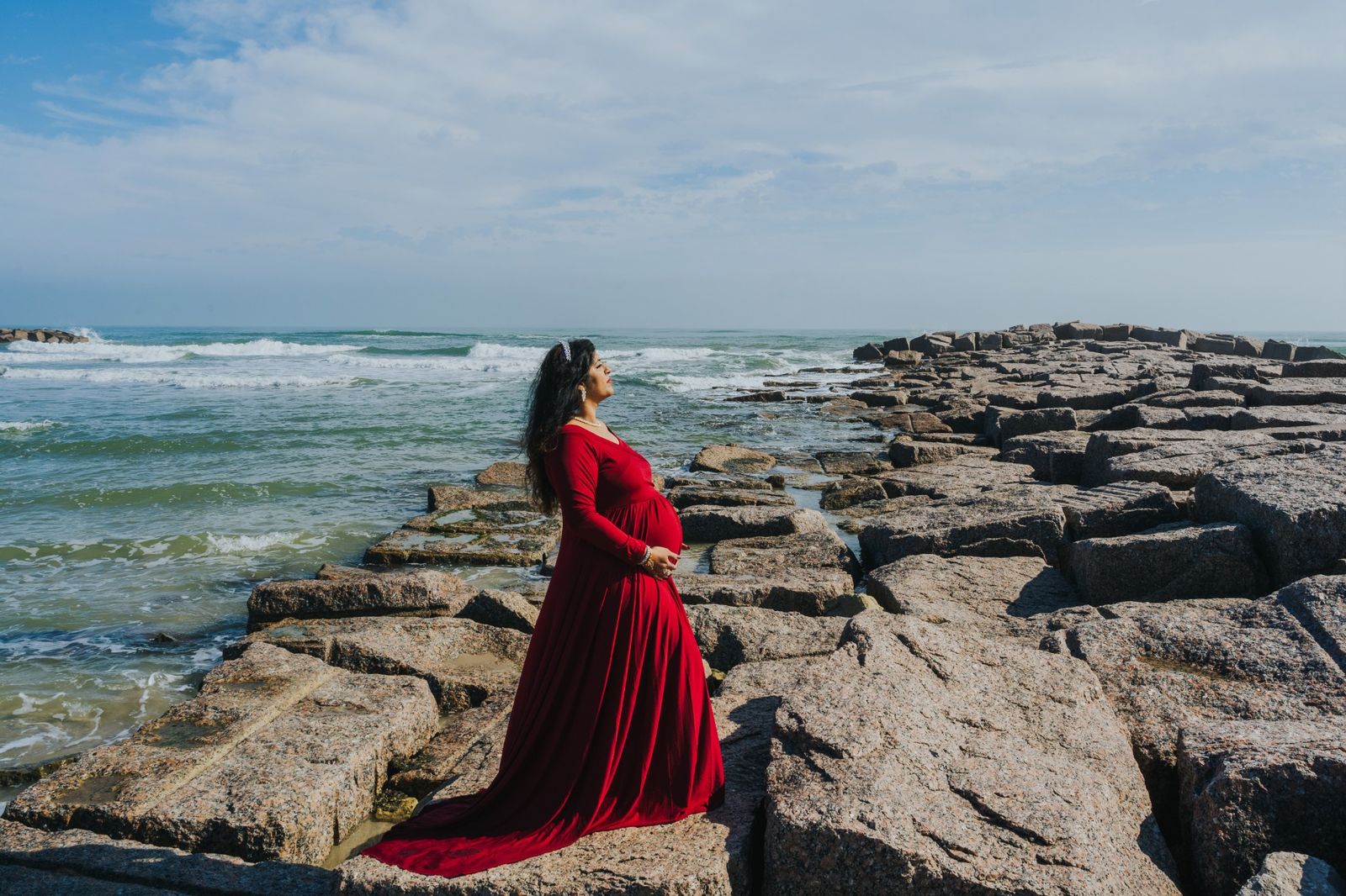 A stunning woman in a red dress standing on Fish Pass Jetty in Mustang Island