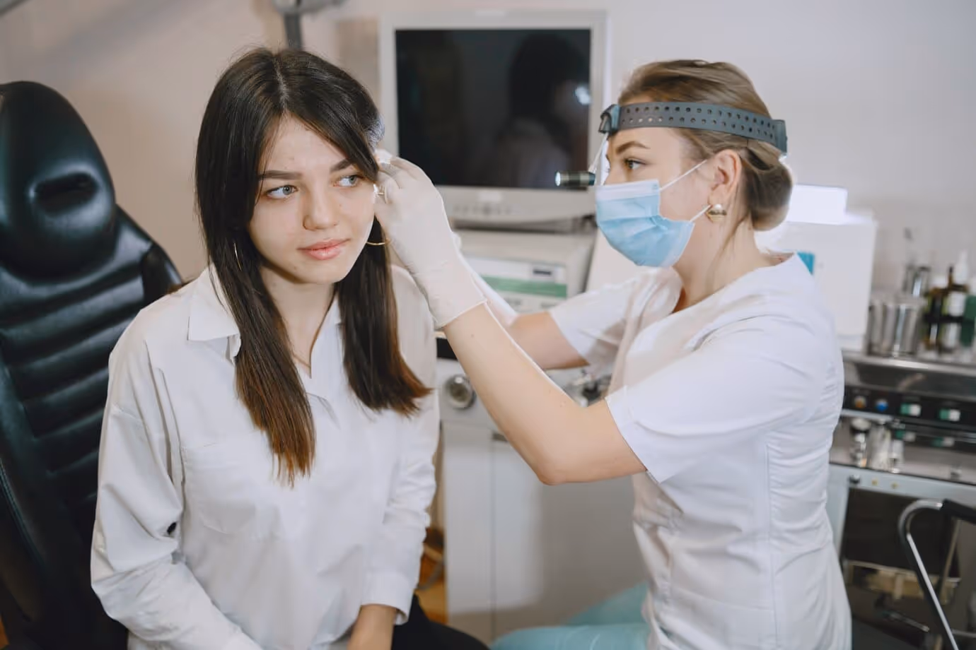 An young audiologist remove earwax from a young lady