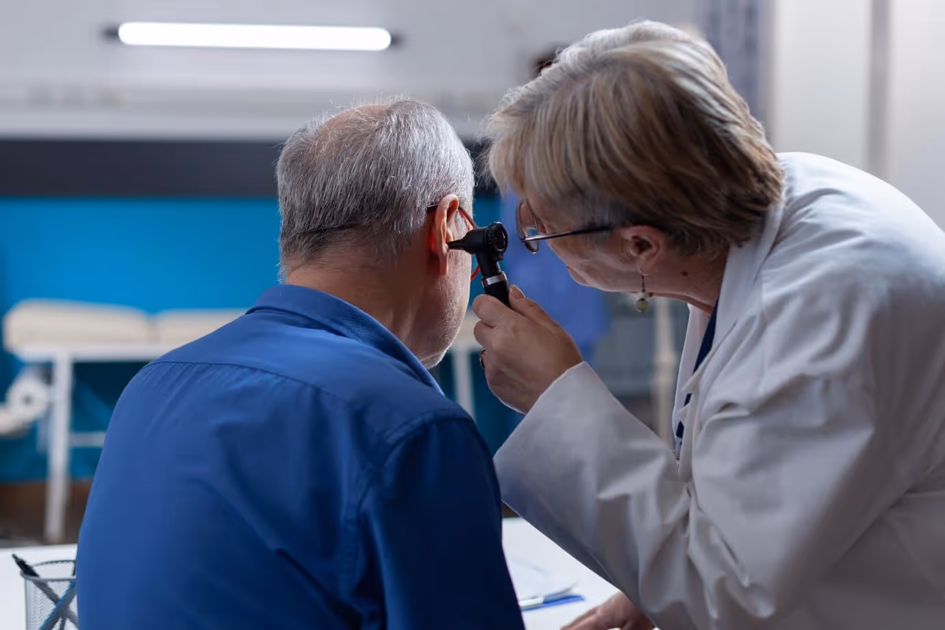 An expert audiologist remove earwax from a older person