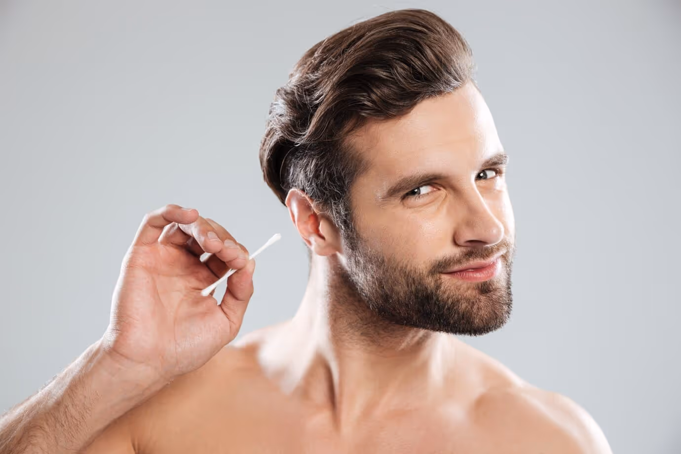 A young person smile while he is trying remove earwax  by himself
