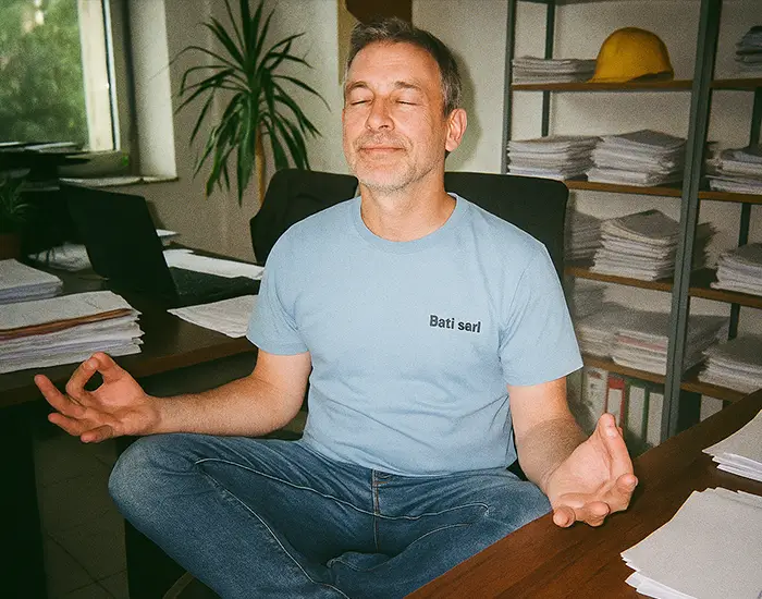 Portrait d'un artisan zen en position de yoga car il gère son entreprise dans la conformité et la légailité avec Batappli, dans son bureau