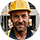 Terrassier souriant portant un casque jaune de chantier avec un arrière-plan flou de chantier extérieur.