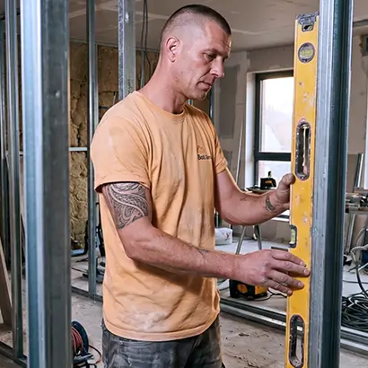 Un artisan utilisant un niveau à bulle sur une structure métallique dans un chantier en construction.