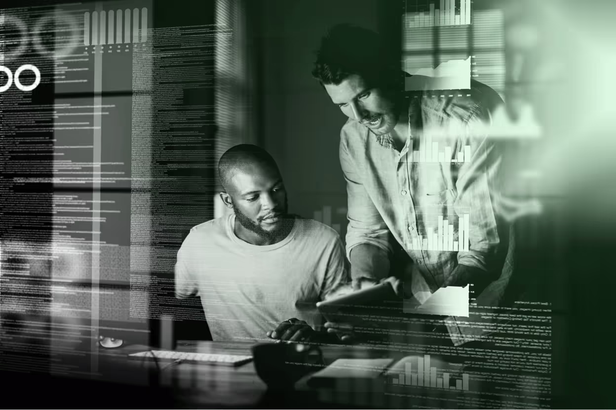 Two coworkers review data at a computer amid translucent charts and interface graphics, conveying focused analysis in a green-toned scene.