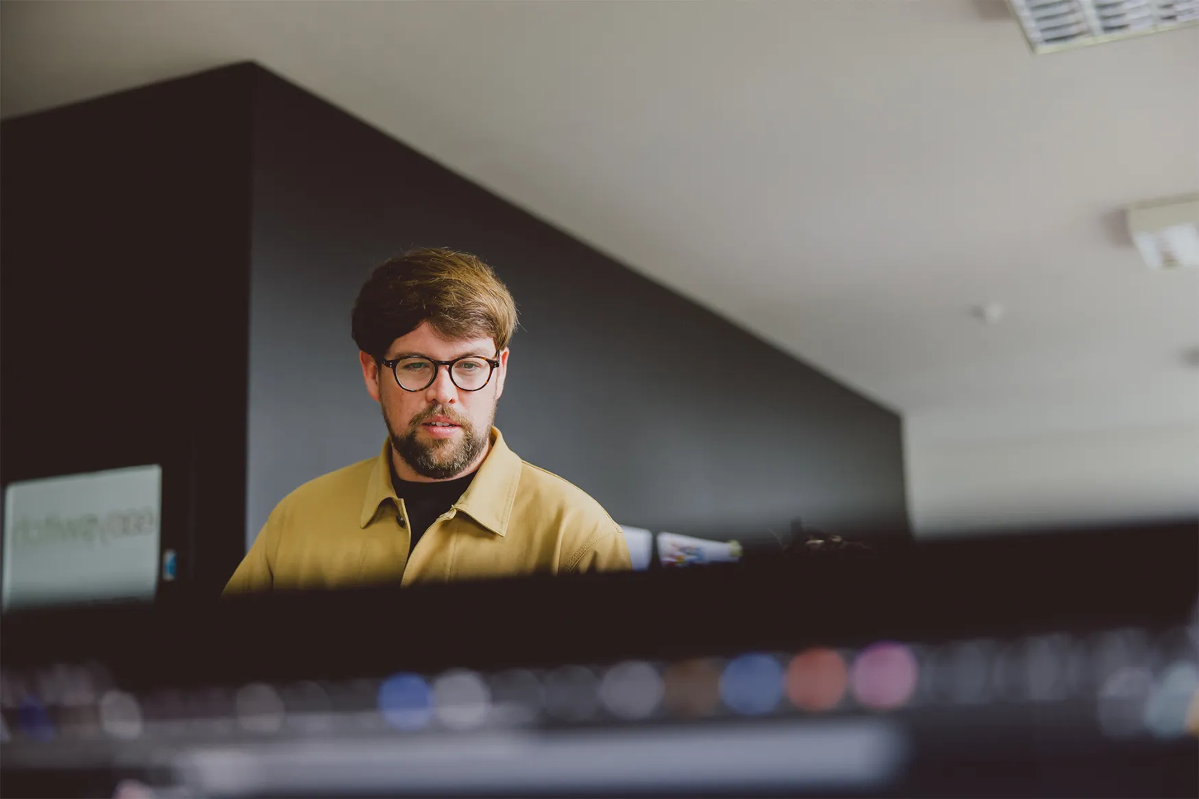 Lee at a computer screen in an office with dark walls.
