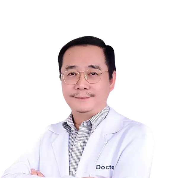 Man wearing glasses, a checkered shirt, and a white doctor's coat standing with arms crossed.