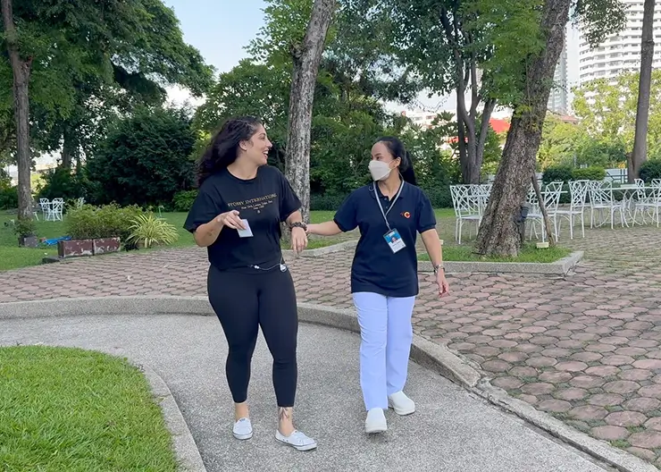 Patient and nurse walking in a lush outdoor park

