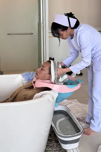 Nurse is washing hairs of a patient.