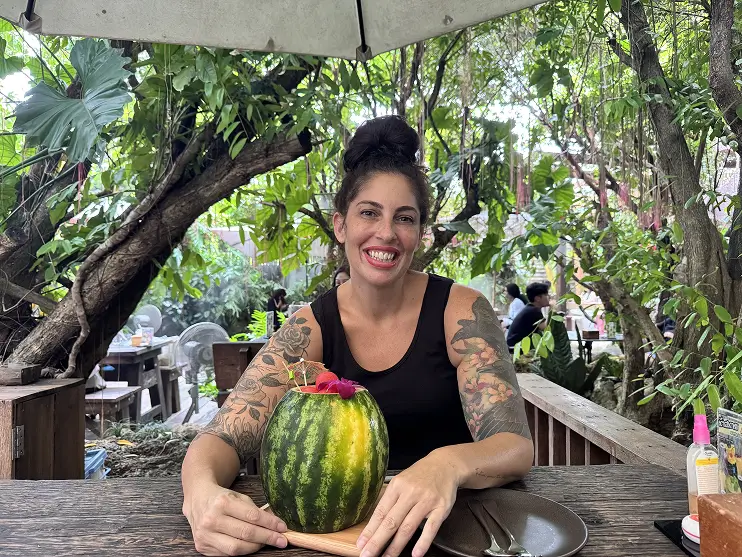 Woman smiling while holding a watermelon outdoors