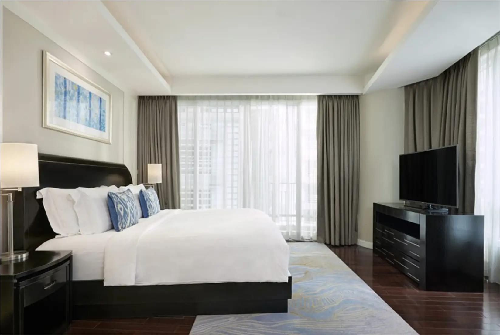Bright bedroom with large bed, floor-to-ceiling windows, and TV.