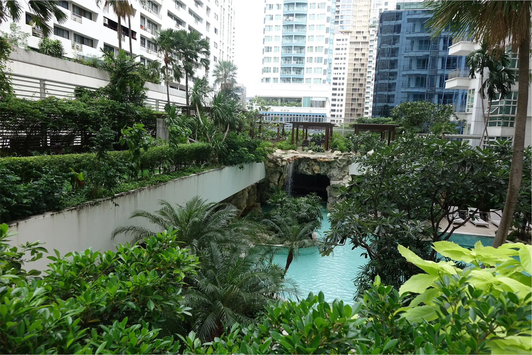 Aerial view of resort-style pool with waterfall and wooden cabanas.