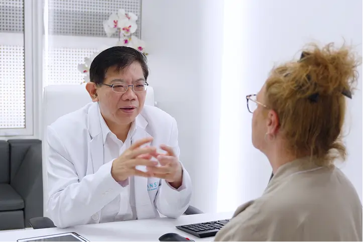 Doctor speaking with a patient during a medical consultation in a clinic room.