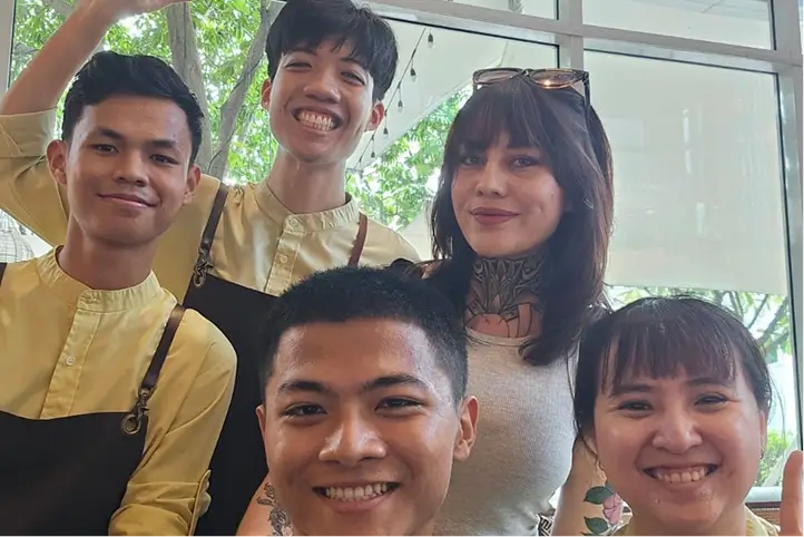 Group photo of smiling staff members posing together inside a café.