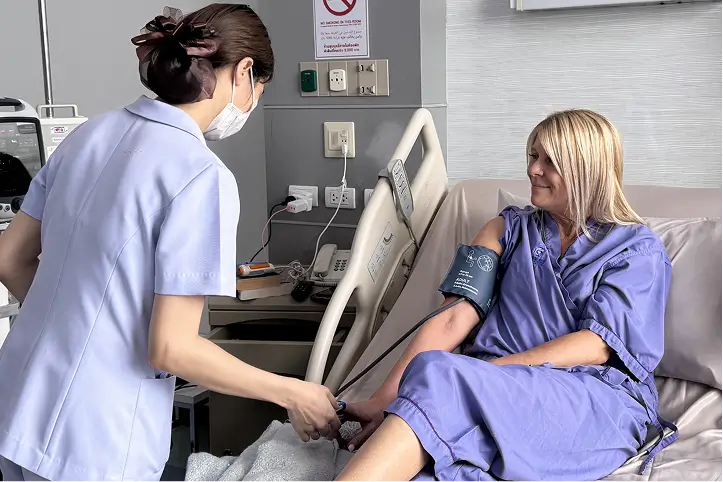 Nurse checking a patient’s blood pressure in a hospital room.