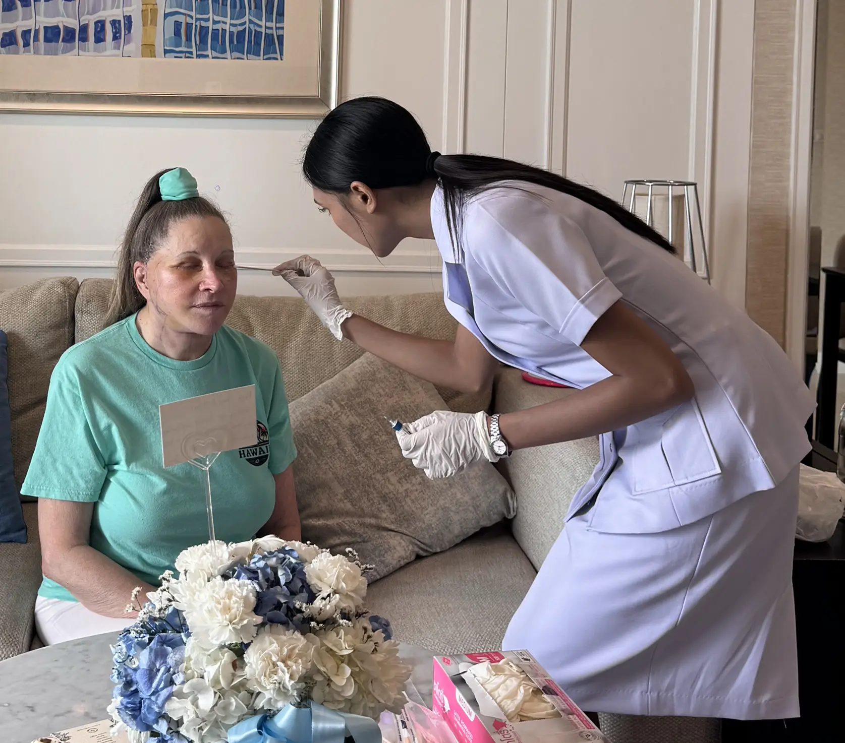 Healthcare worker wearing gloves cleaning a woman's face.