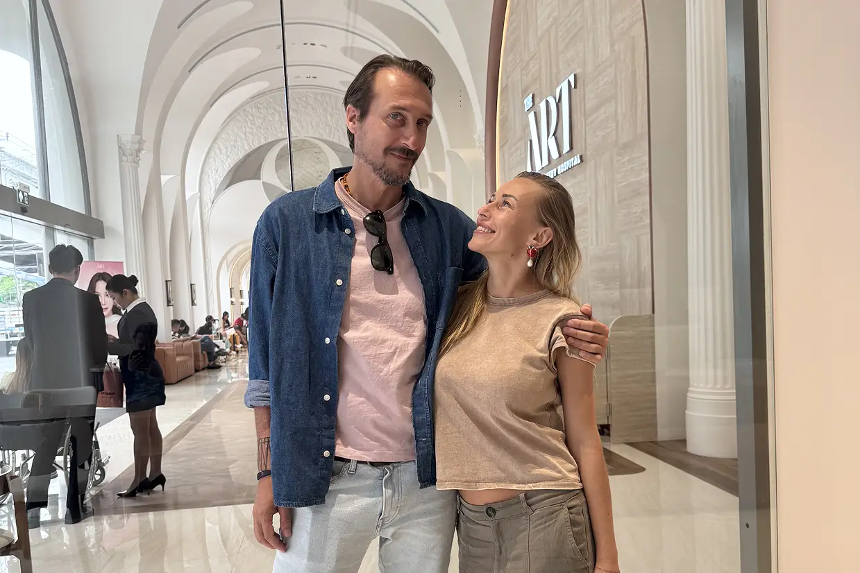 Man and woman standing close together indoors, the woman smiling up at the man.