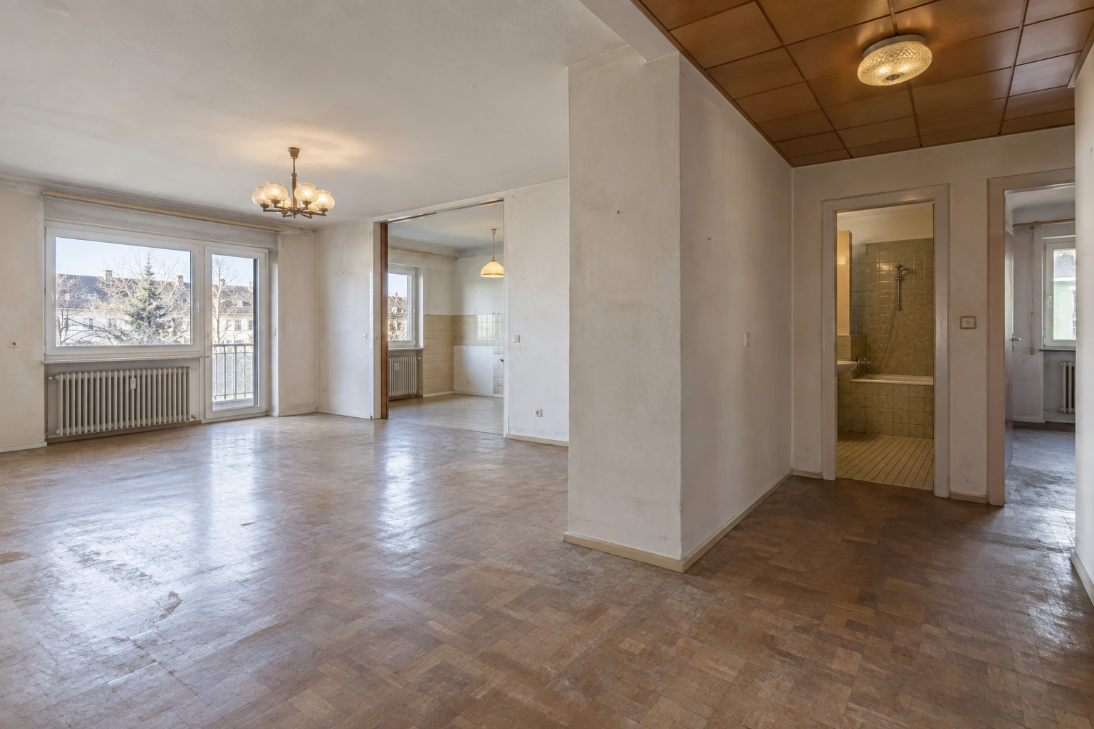 Illustrativer Wohnungsbestand vor dem Innenausbau mit veralteten Böden, Wandoberflächen, Deckenbekleidung, Beleuchtung und Badzugang