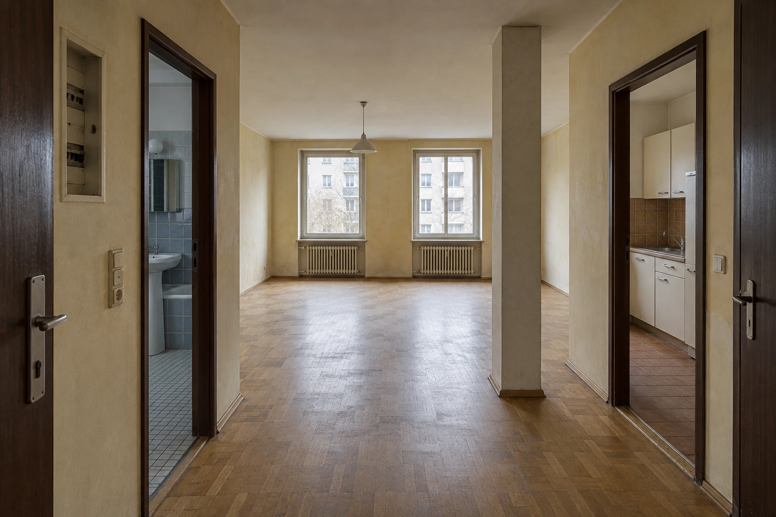 Münchner Eigentumswohnung vor der Sanierung mit abgenutztem Holzparkett, geschlossener Küche, veraltetem Badezimmer und älteren Elektroeinbauten