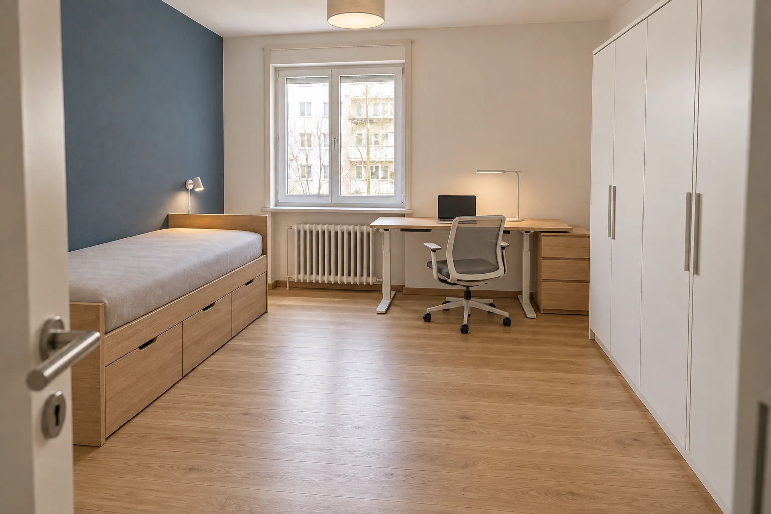 Illustrative Montagephase desselben Zimmers mit blauer Akzentwand, Bett mit Schubladen, verstellbarem Fensterarbeitsplatz, geschlossenem Schulstauraum und drei abgestimmten Lichtquellen