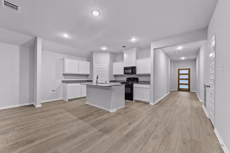 Open layout kitchen and living room with a view of the front door