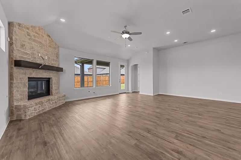 Living room with windows, dining area, ceiling fan and fireplace in corner with brick