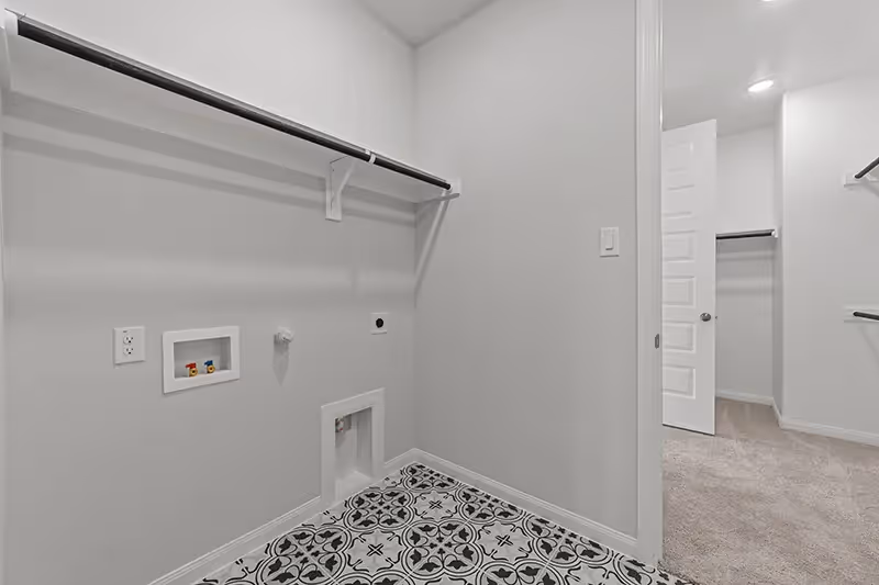 Laundry room with clothes rod and patterned tile