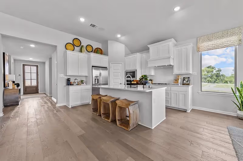 kitchen that opens to dining and living area with white cabinets and light counters