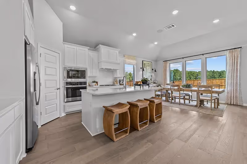 kitchen that opens to dining and living area with white cabinets and light counters