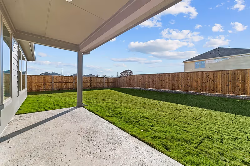 covered back patio and grassy backyard