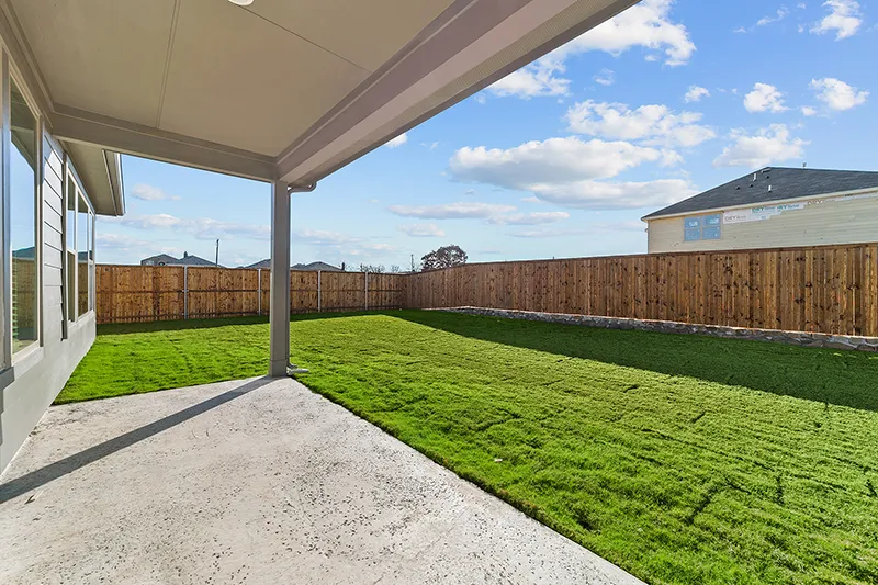 covered back patio and grassy backyard