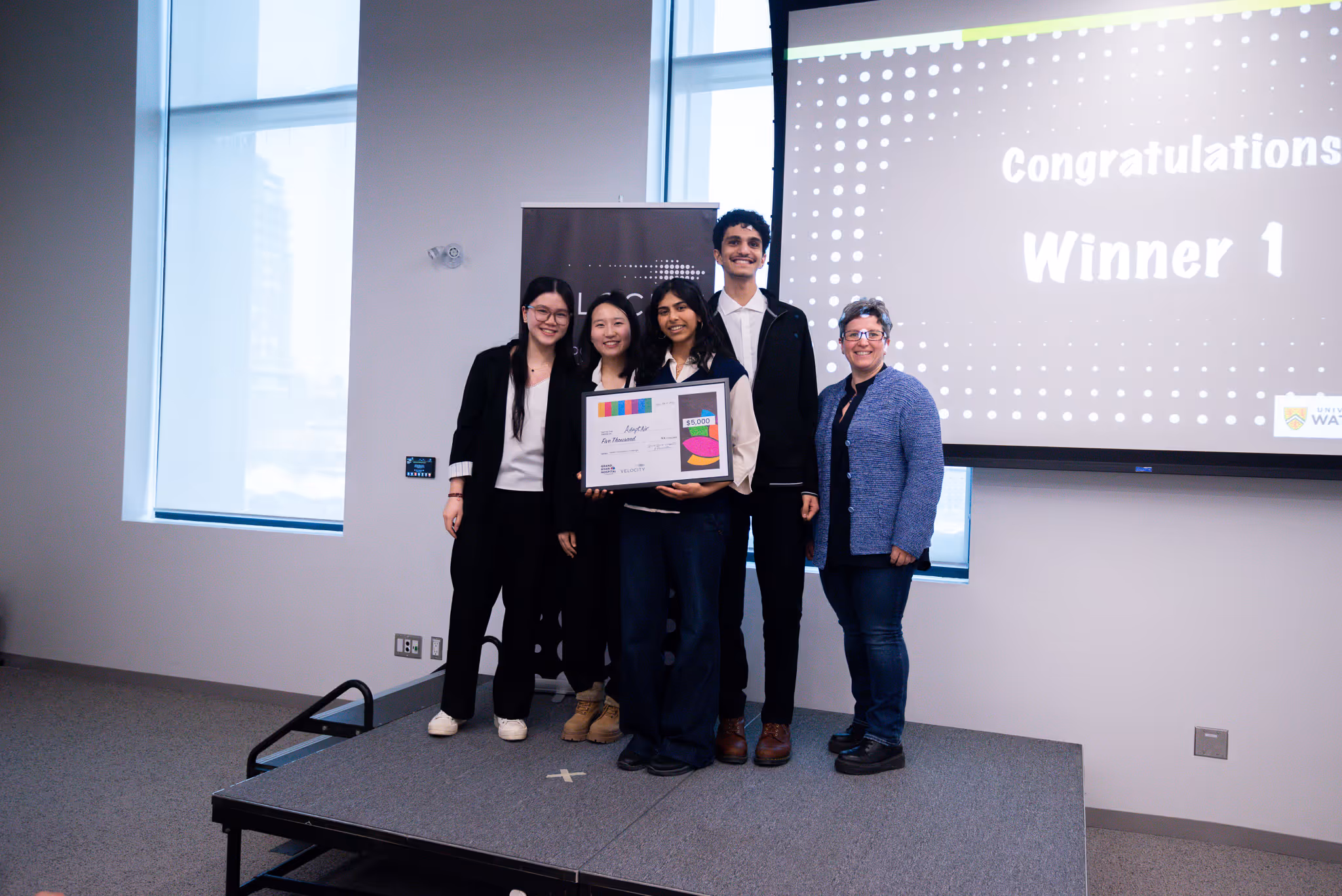Group of students in front of screen with cheque