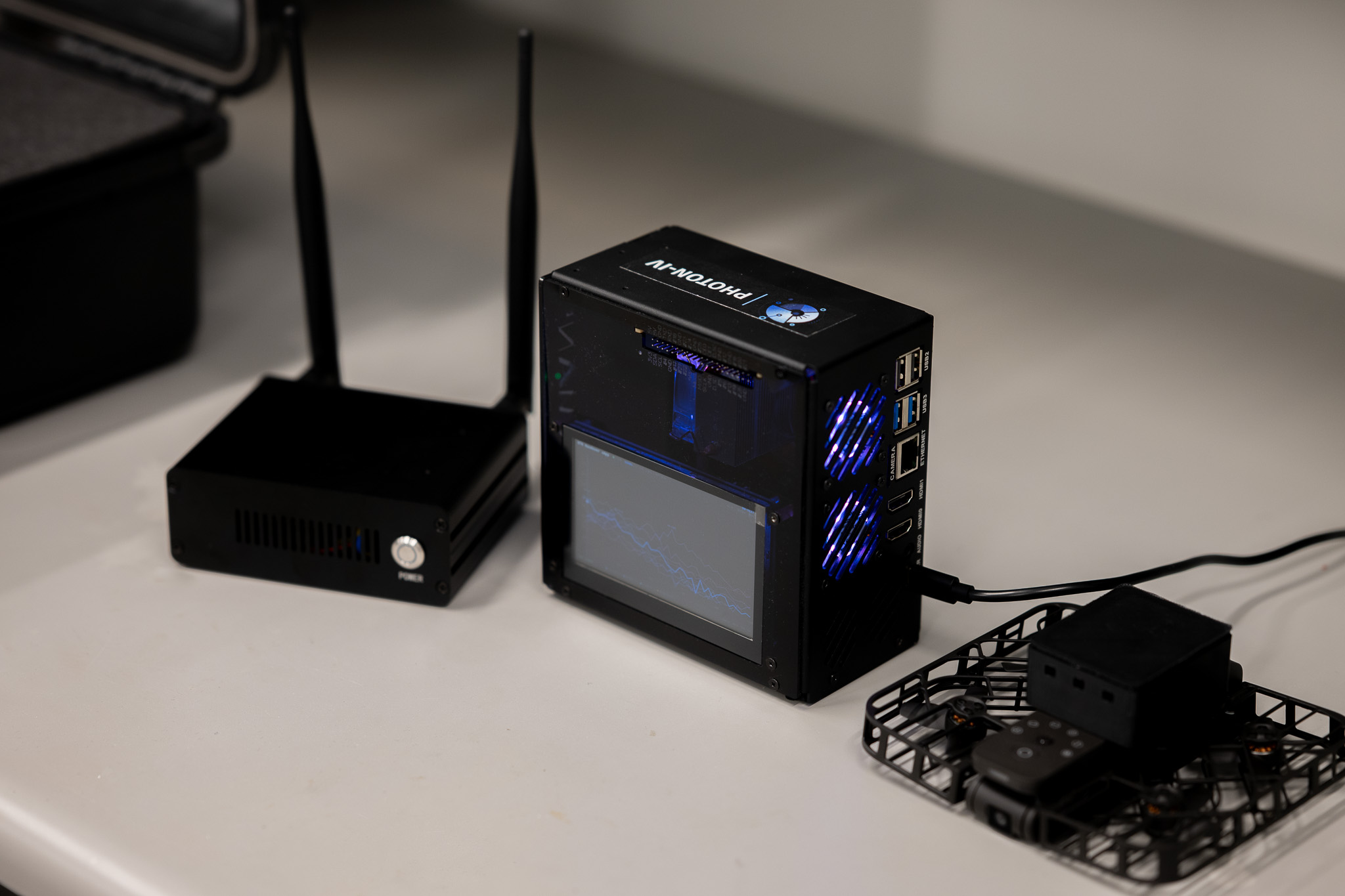 Photon-IV product lineup displayed side by side on a table, featuring Predict for IoT-NTN battery intelligence, Stellarlink for 5G-NTN edge connectivity, and Swarmnet for next-generation drone communications.