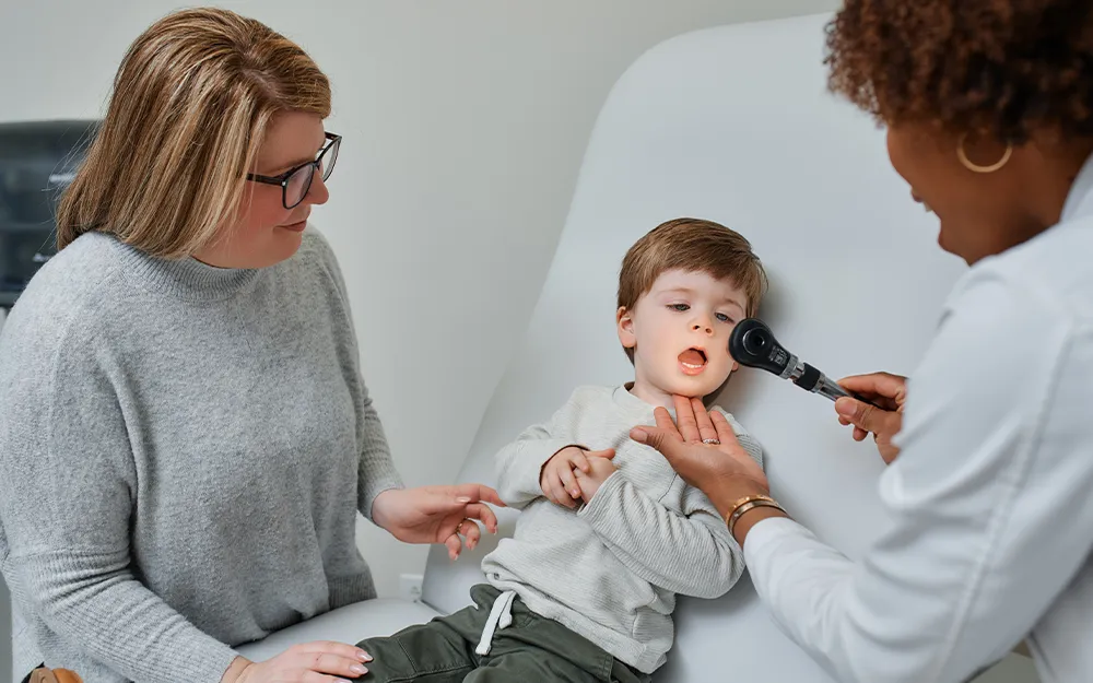 Dr. Gayon Hyatt examines a cute little boy while his mother looks on during a well-child visit in East Brunswick