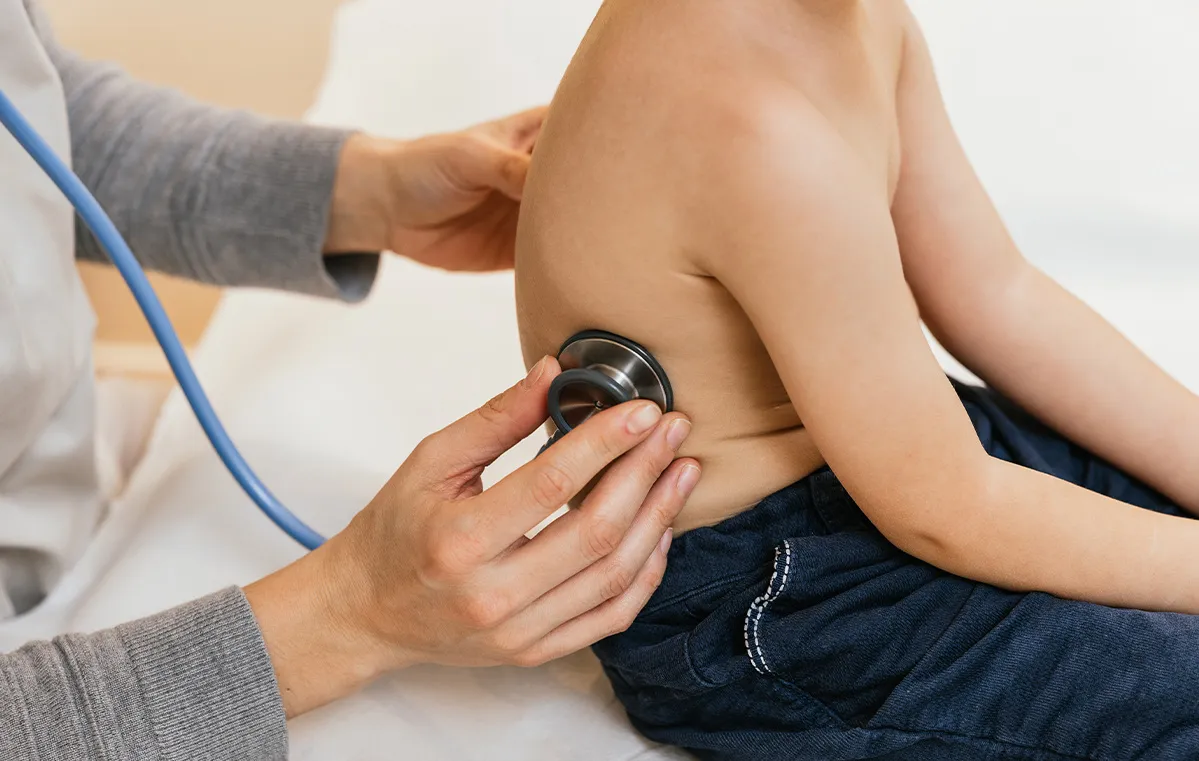 Closeup of a doctor examining a child’s abdomen with a stethoscope at a well-child visit in East Brunswick