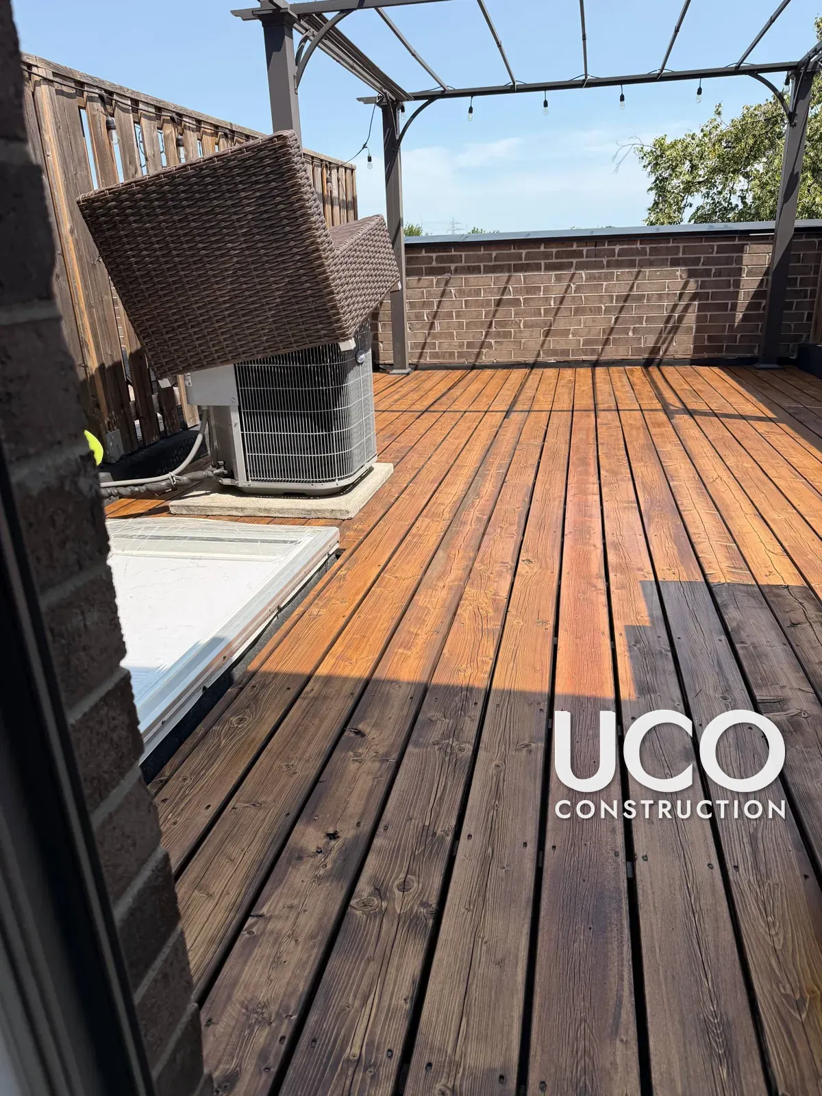 Rooftop Deck Restoration in Toronto: Grey Weathered Rooftop Terrace Decking Sanded to Bare Wood and Refinished in a Warm Oil-Based Stain Around the Pergola, A/C Unit and Skylight