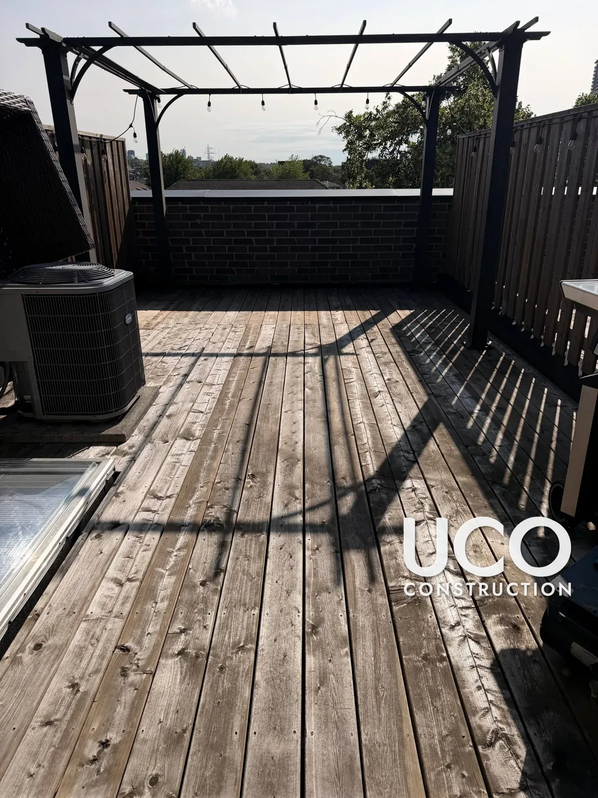 Rooftop Deck Restoration in Toronto: Grey Weathered Rooftop Terrace Decking Sanded to Bare Wood and Refinished in a Warm Oil-Based Stain Around the Pergola, A/C Unit and Skylight