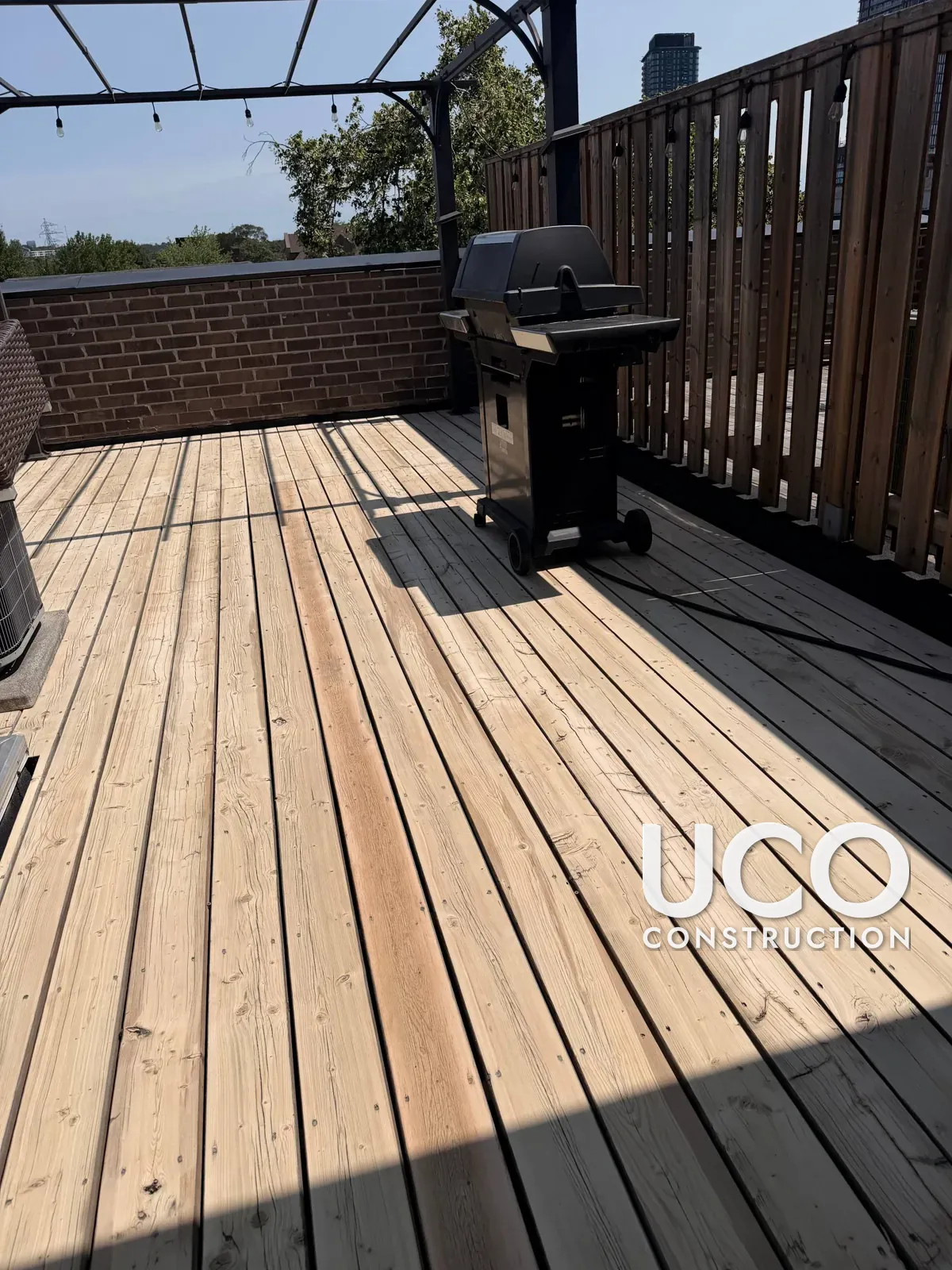 Rooftop Deck Restoration in Toronto: Grey Weathered Rooftop Terrace Decking Sanded to Bare Wood and Refinished in a Warm Oil-Based Stain Around the Pergola, A/C Unit and Skylight