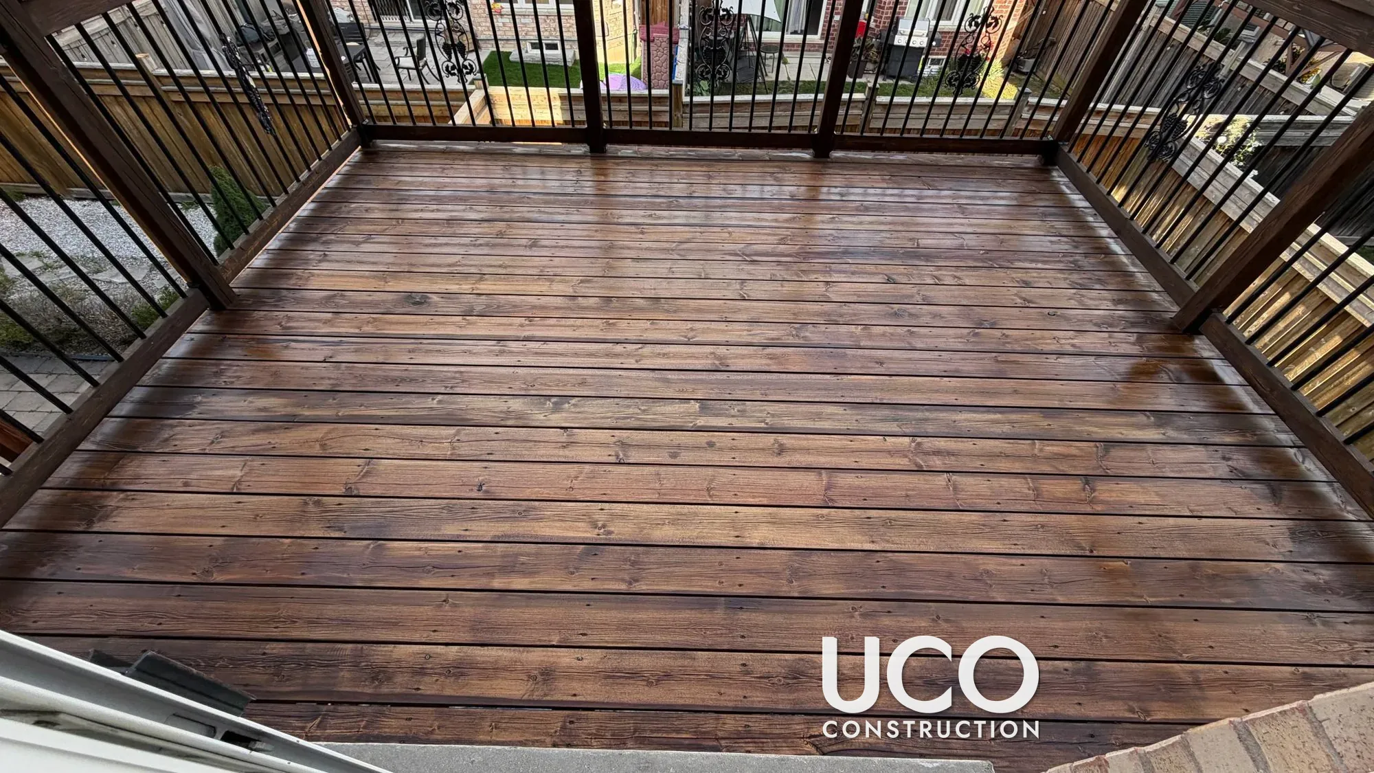 Grey Deck Restored in Maple: Weathered Pressure-Treated Deck Sanded and Stained Dark with an Oil-Based Finish