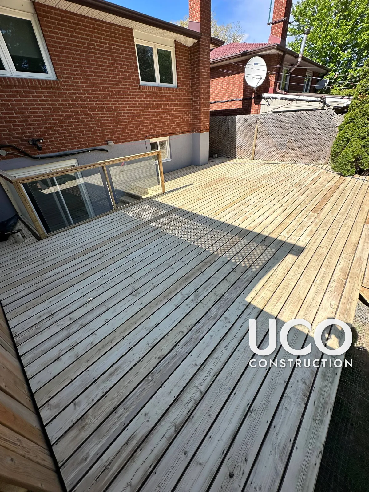 Deck Staining in Etobicoke: Large Weathered Backyard Deck With Glass Railing Sanded and Refinished in a Warm Brown Stain