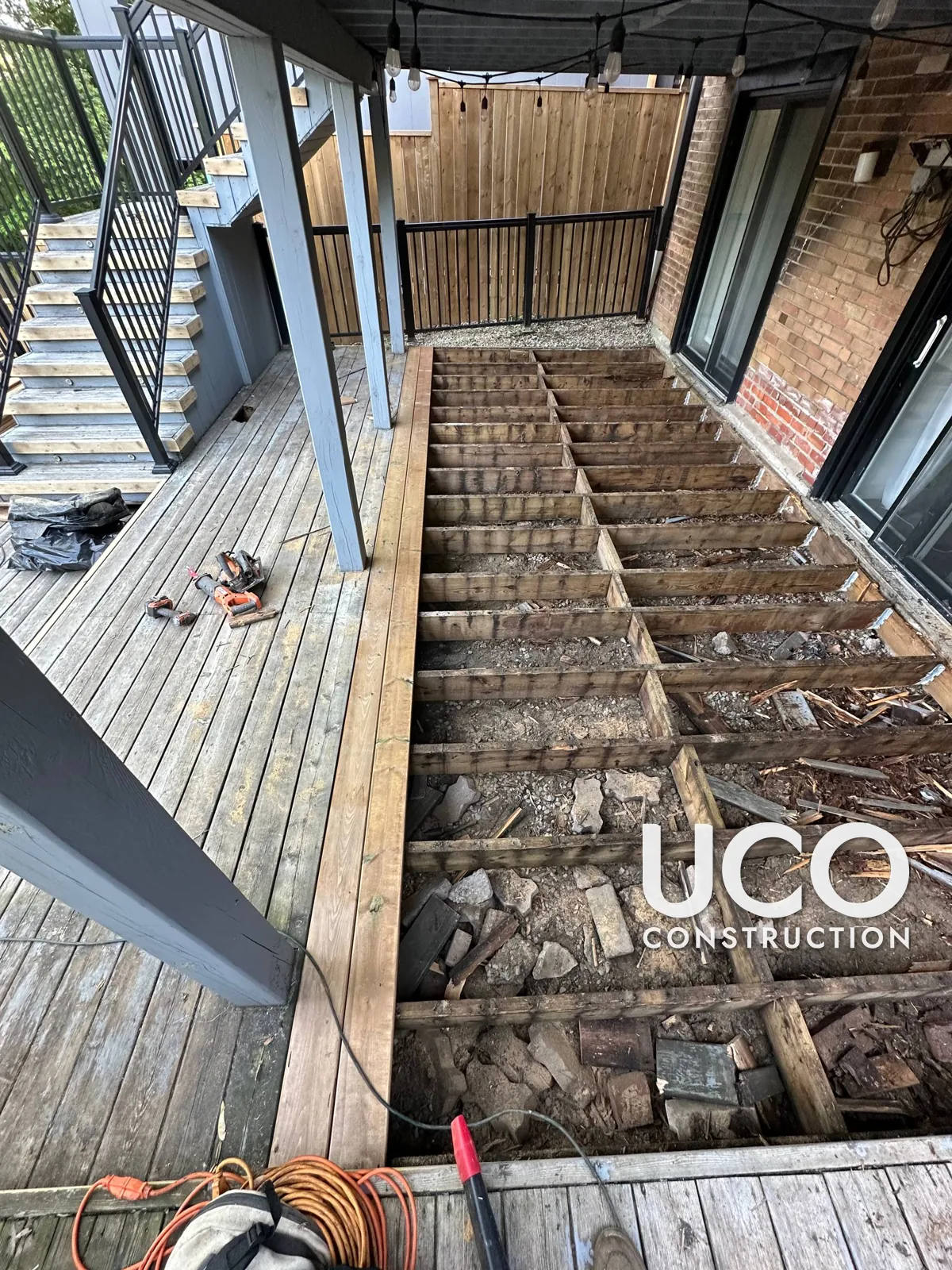 Deck Repair and Staining in Toronto: Rotted Deck Section Under a Balcony Rebuilt With Properly Gapped Boards, Then Sanded and Stained
