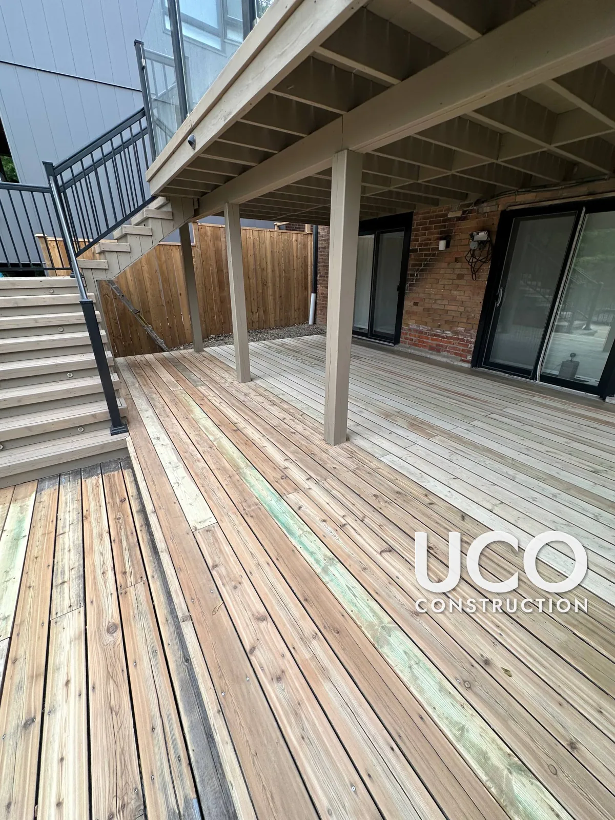Deck Repair and Staining in Toronto: Rotted Deck Section Under a Balcony Rebuilt With Properly Gapped Boards, Then Sanded and Stained
