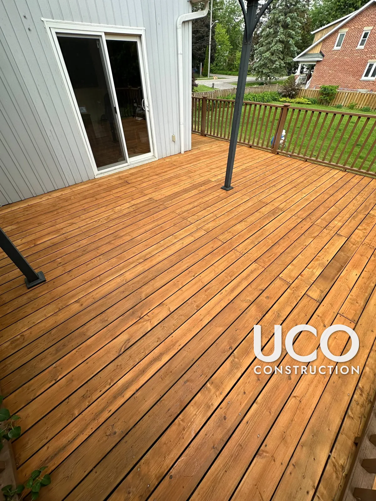 Deck Staining in Pickering: Large Deck With Peeling Grey Solid Stain Sanded to Bare Wood and Refinished in a Golden Cedar Stain, Railings Refreshed in Brown