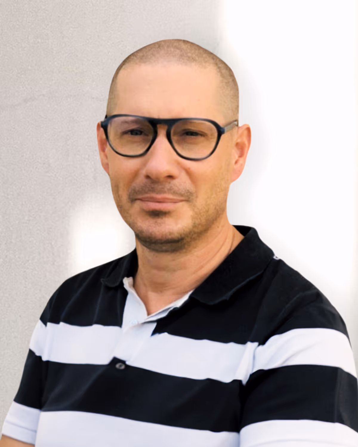 Man with short hair wearing black-framed glasses and a black and white striped polo shirt.